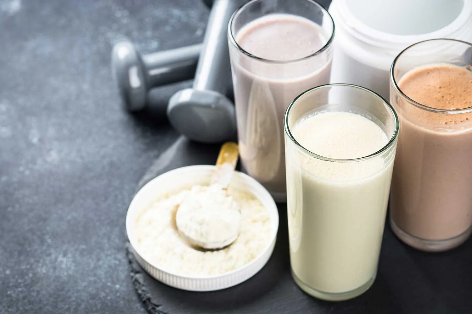 Healthy meal replacement shakes with protein powder, dumbbells and powder.