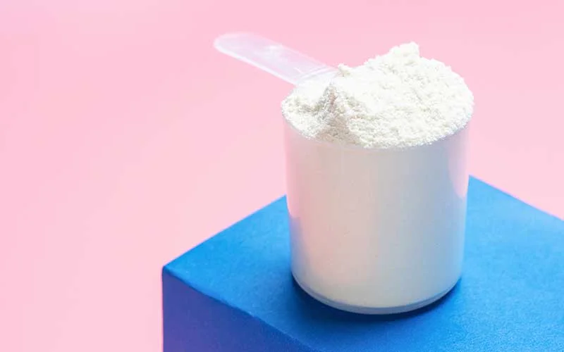 Collagen Powder and Measuring spoon on pink and blue background.