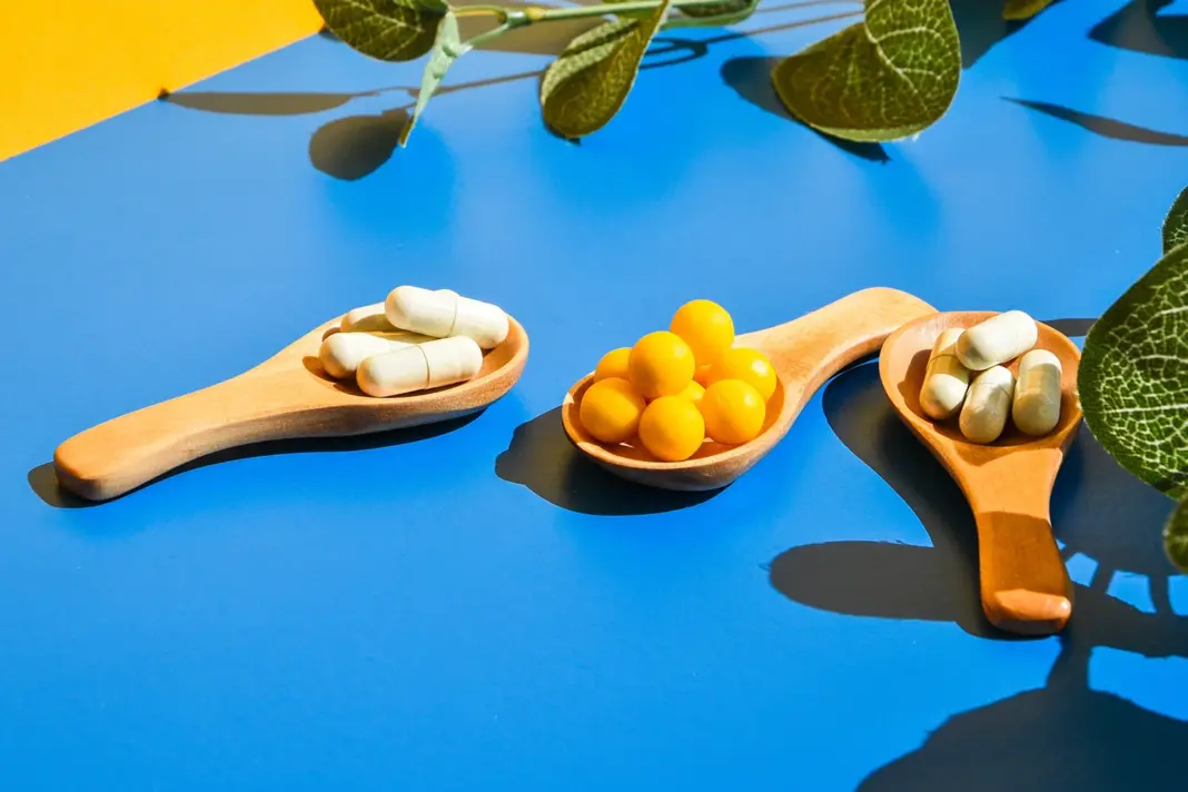 Basic Probiotics on wooden spoon on blue and yellow background.