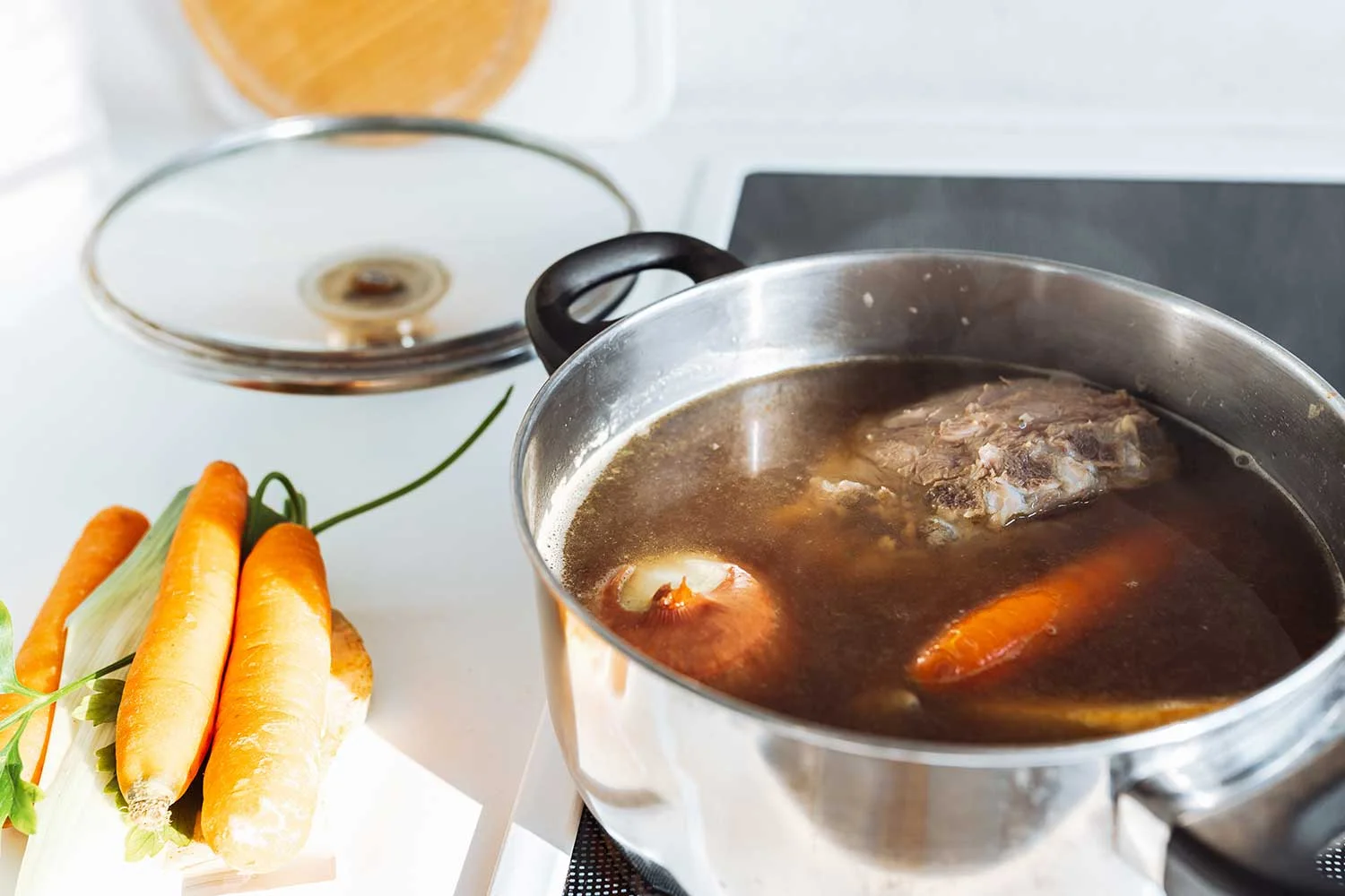 Homemade bone broth with vegetables in kitchen