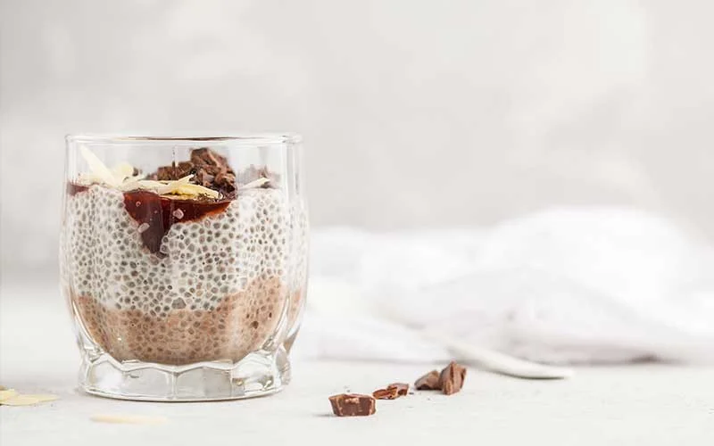 Chia pudding with chocolate, almonds and berry jam, white background. Raw vegan dessert.