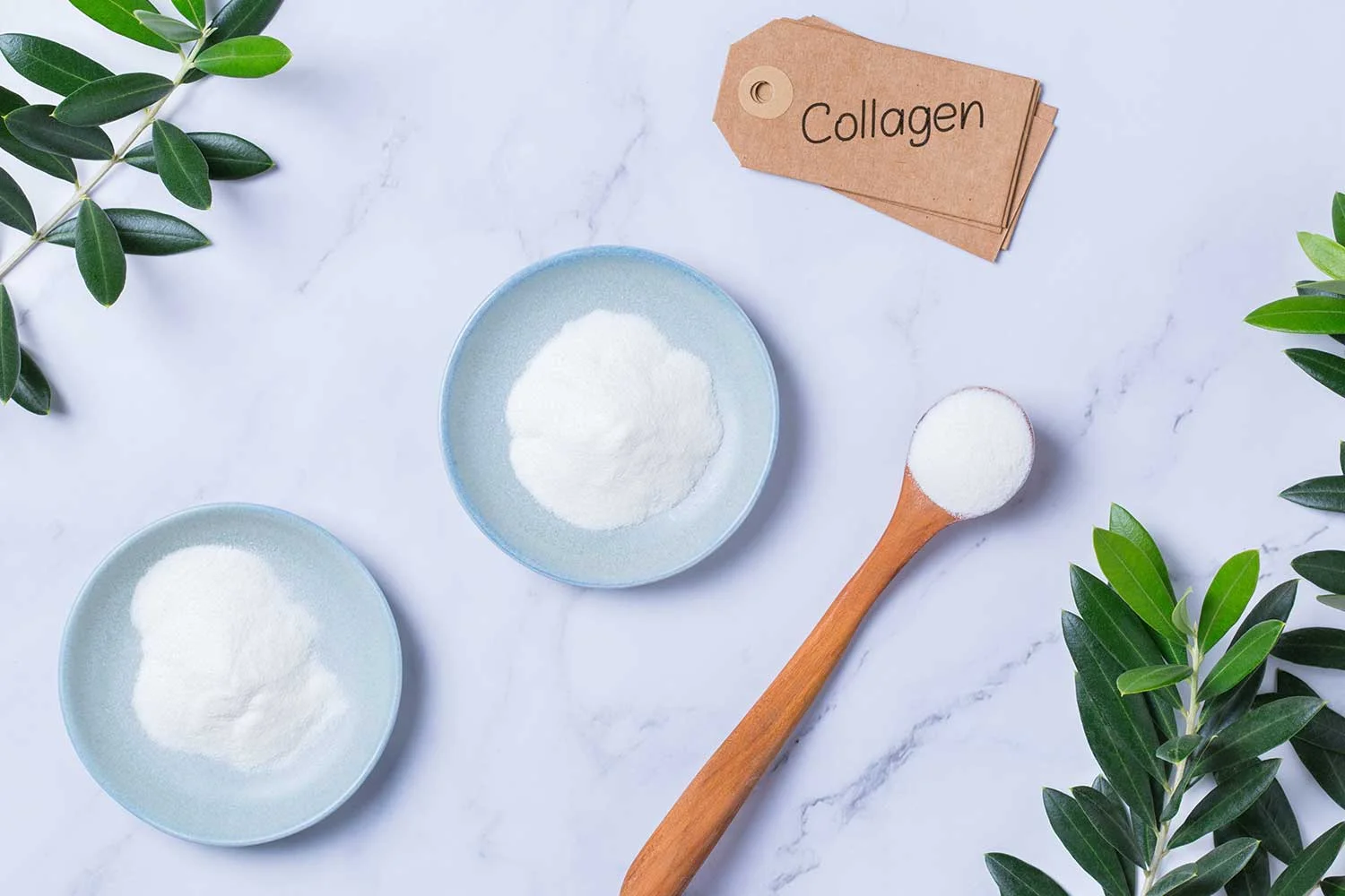 collagen peptides powder in a glass bowl with a wooden spoon.