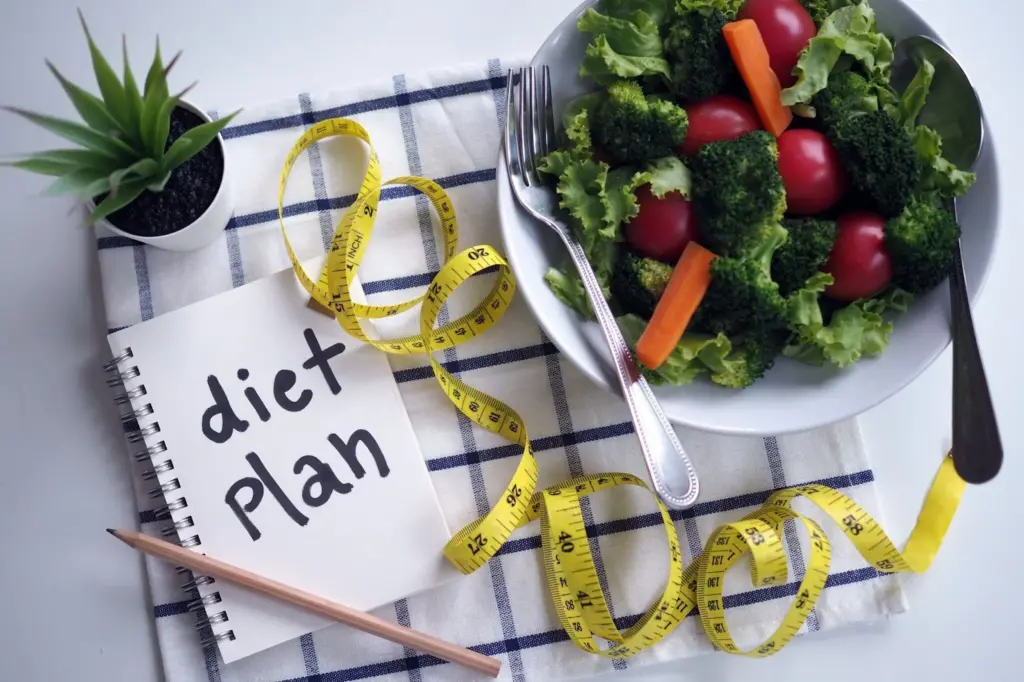 Healthy eating concept. Vegetable salad, food control notebook and tape measure