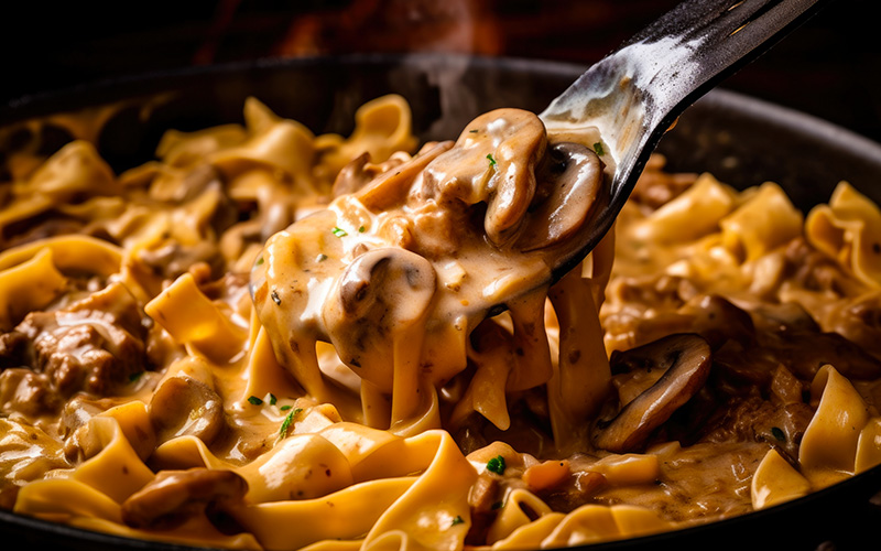 A wooden spoon scooping a generous serving of beef stroganoff from a pan, with steam and the aroma of the dish wafting from the spoon