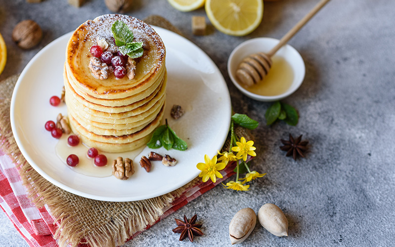 Gluten-free Pancakes with cranberries, lemon, and honey on a gray background