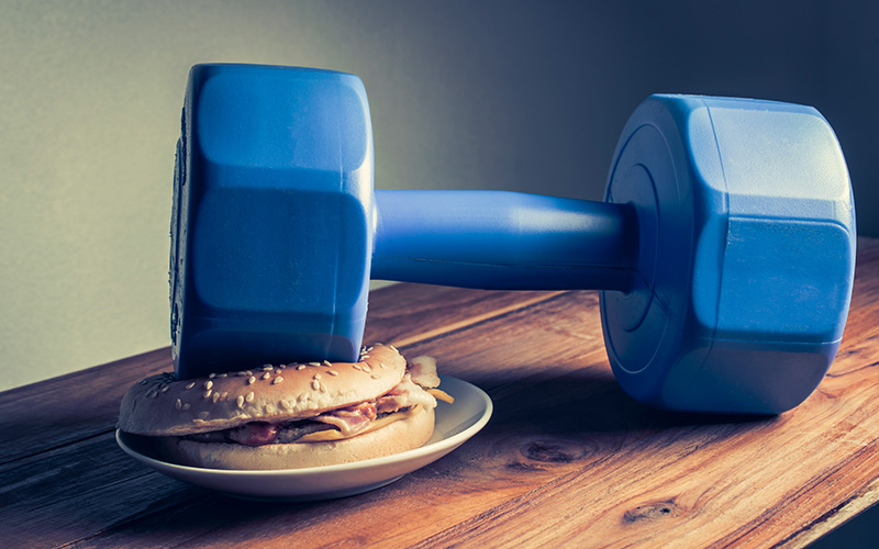 Blue dumbbell on top of a hamburger on a wooden table