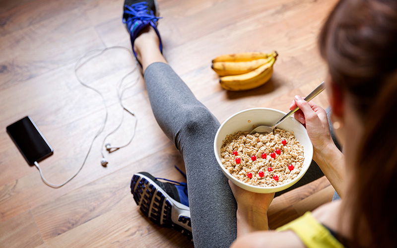 Young girl eating a bowl of oatmeal with berries after a workout