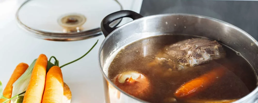 Homemade bone broth with vegetables in kitchen