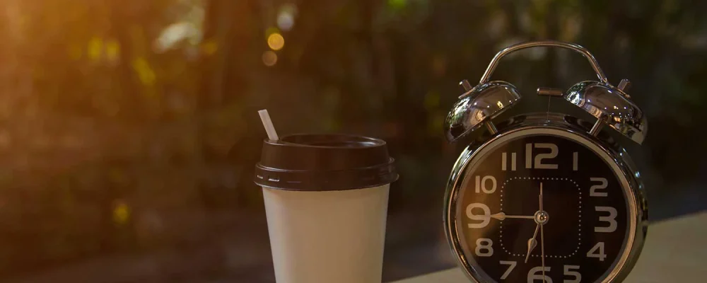 Alarm clock with a cup of meal replacement shake in the morning sunlight