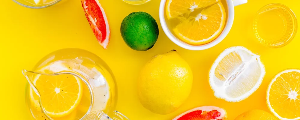 lemonade drink with lemon, lime, grapefruit on yellow background