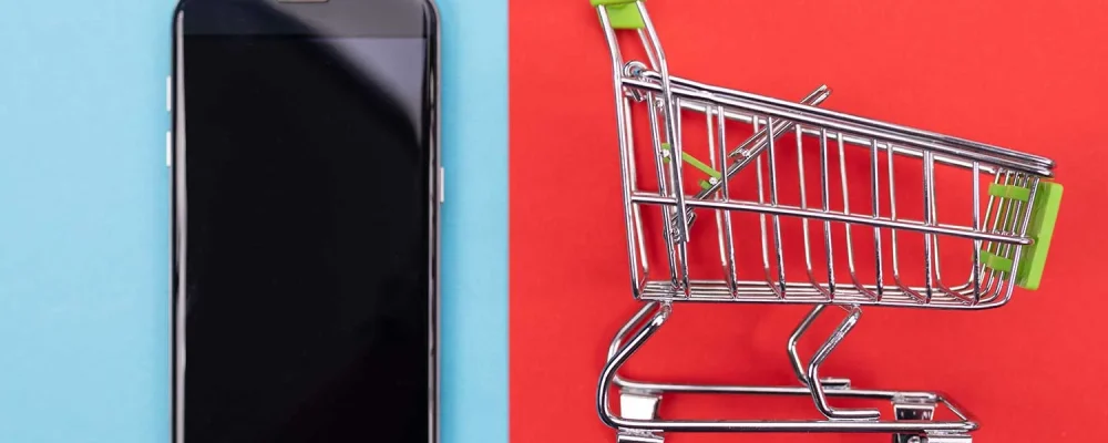 Smartphone and self-service supermarket trolley cart with green handle on colorful background