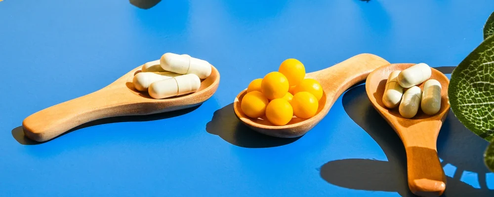 Basic Probiotics on wooden spoon on blue and yellow background.